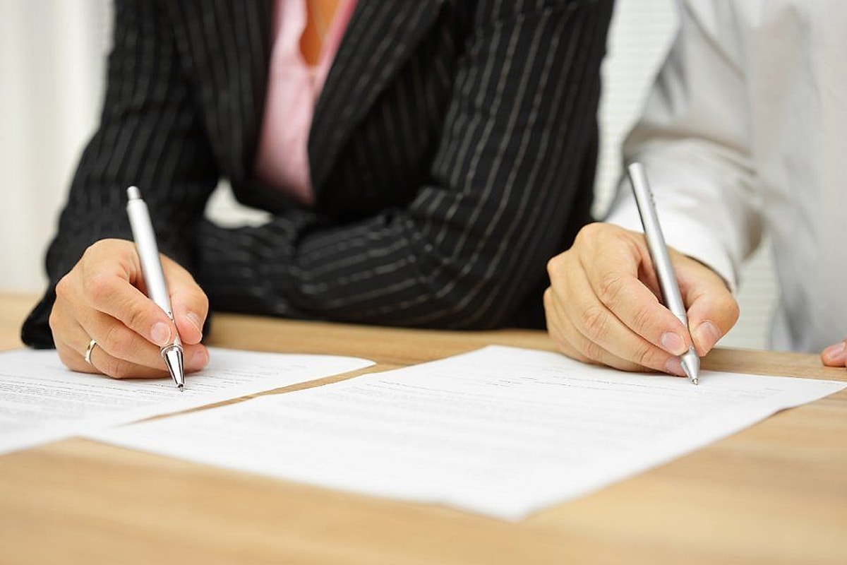 Due persone firmano un accordo alla scrivania