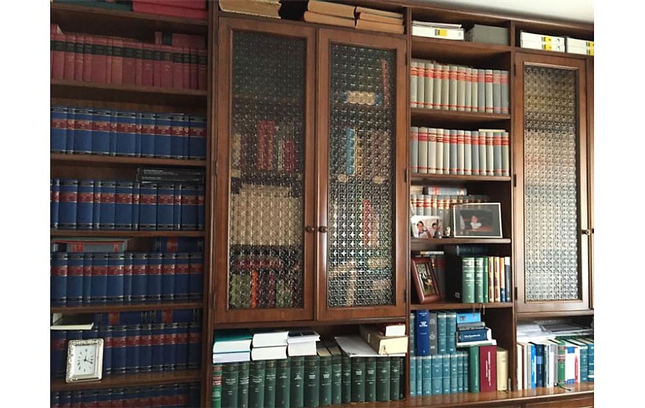 La libreria a vetri dello studio, con i volumi di giurisprudenza e le fotografie di famiglia